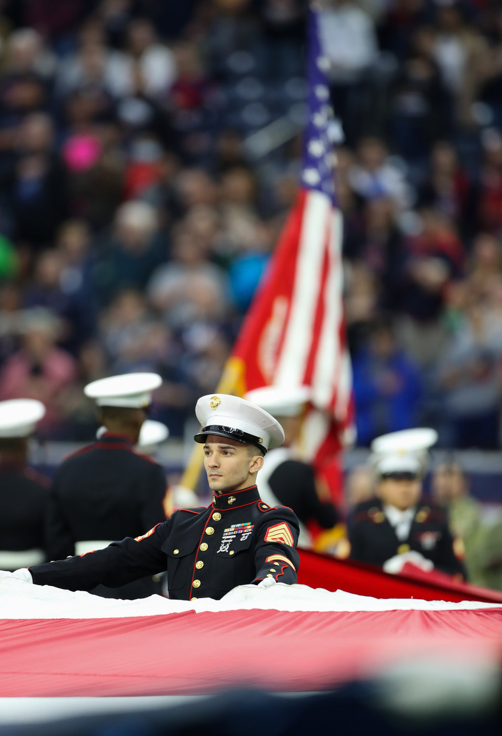 A United States Marine is part of a group of service members holding the U.S. flag before an NFL game between the Houston Texans and the New York Jets on November 28, 2021 in Houston, Texas. The Jets won, 21-14
