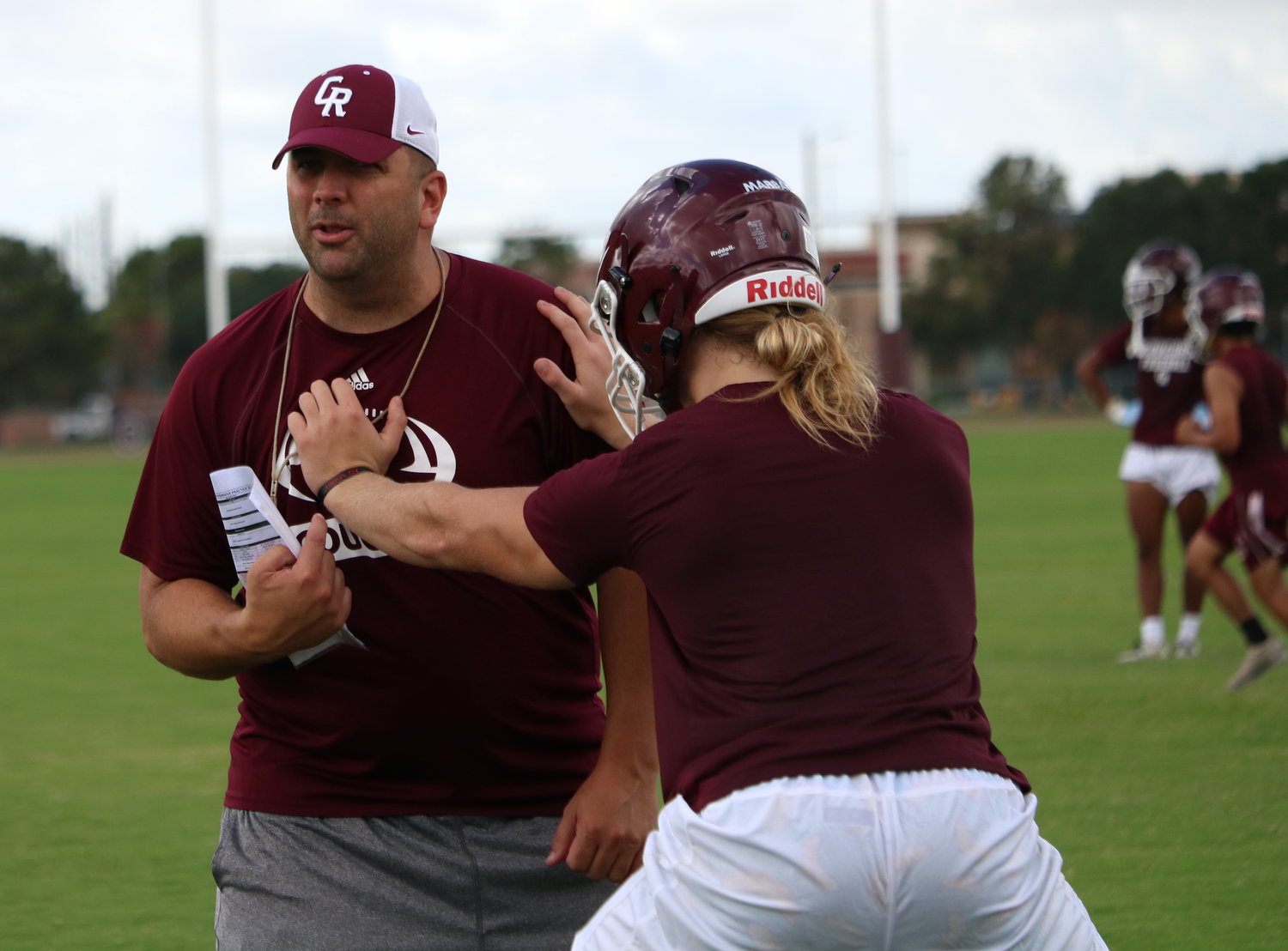 Cinco Ranch head coach Chris Dudley explains a drill to a group of lineman during Monday’s practice.