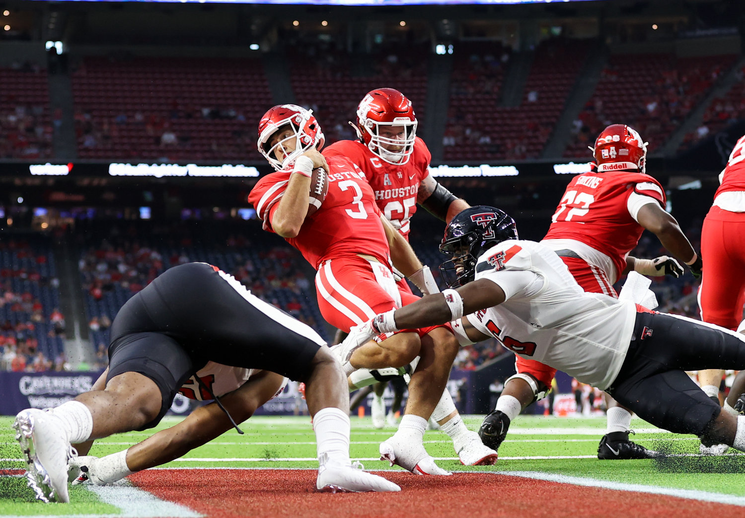 Houston Cougars quarterback Clayton Tune (3) escapes the grasp of Texas Tech Red Raiders linebacker Riko Jeffers (6) in the end zone to avoid a safety during an NCAA football game between Houston and Texas Tech on September 4, 2021 in Houston, Texas.