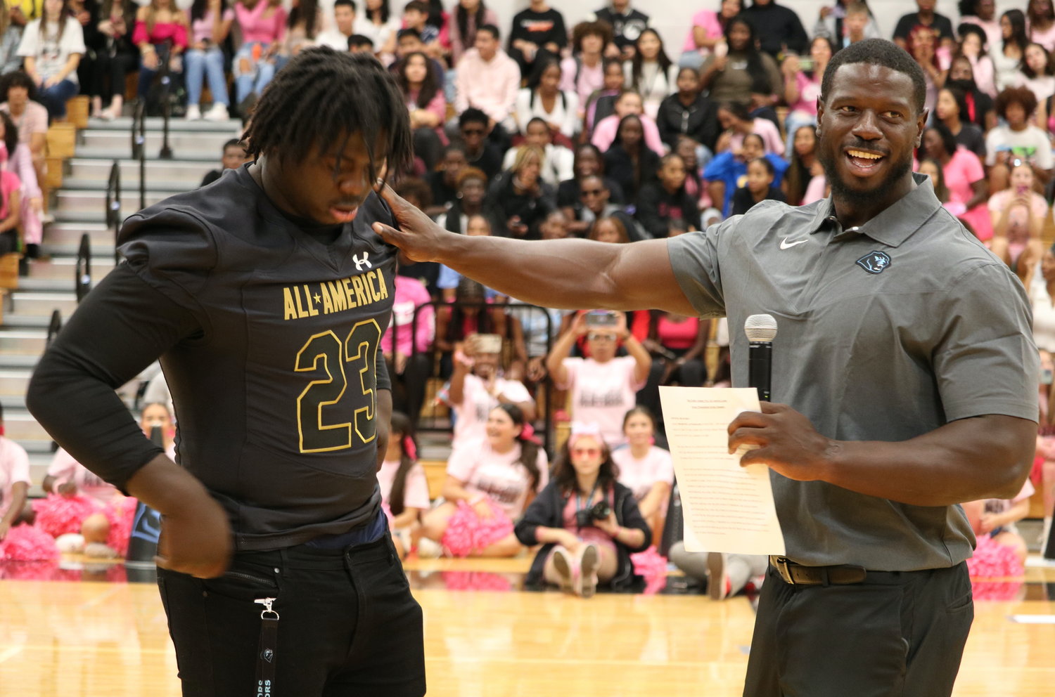 DJ Hicks is presented with his Under Armour All-American jersey as David Hicks Sr. looks on during Friday’ pep rally at the Paetow gym.